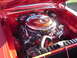 1964 Ford Fairlane - The engine bay of a red car features a prominent 426 Hemi engine with a chrome air cleaner and orange accents.