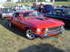 1964 Ford Fairlane - A red 1969 Ford Mustang is parked at an outdoor car show with other vehicles visible.