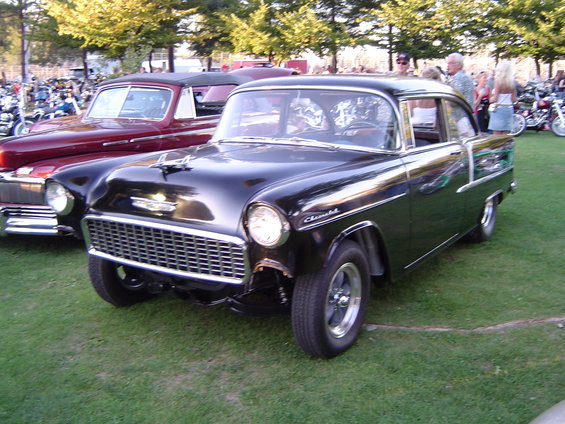 Black 1955 Chevrolet sedan with chrome grille and trim, parked on grass