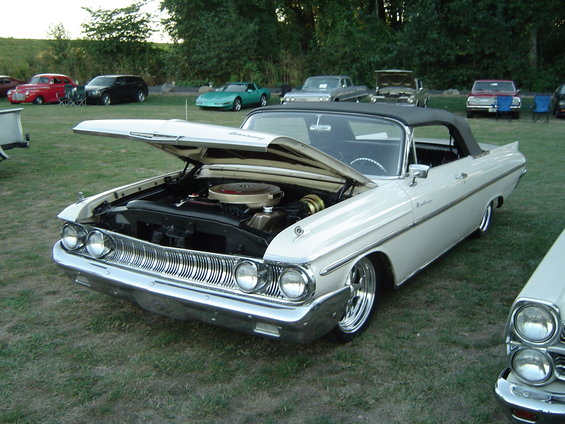 1960 Mercury Monterey convertible with hood open, parked on grass. Another car is partially visible to the right