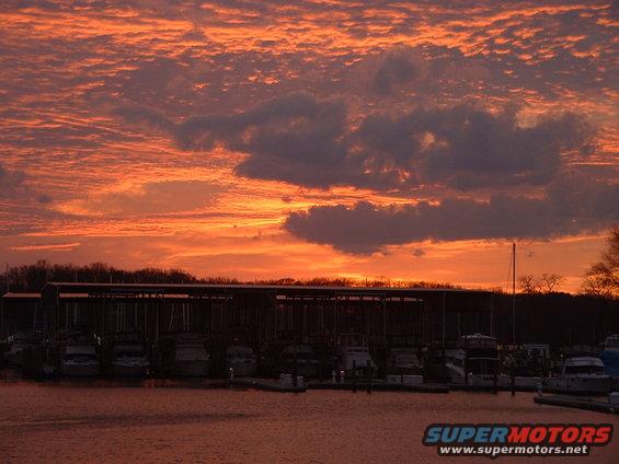 Boats docked at a marina with a colorful sunset sky overhead