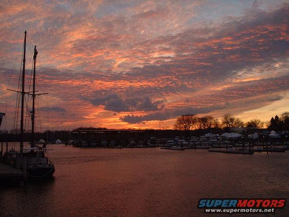 Marina scene at sunset with sailboat and boats docked