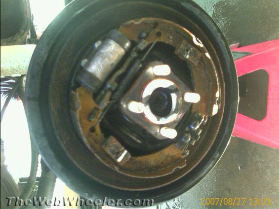 Brake drum assembly with brake shoes and wheel cylinder. Visible rust and wear