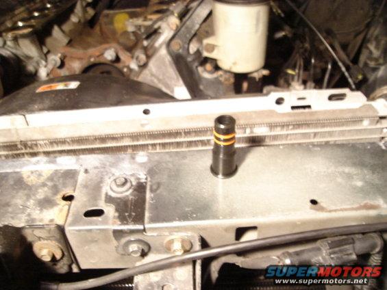 Engine bay showing radiator, coolant reservoir, and a black cylindrical part with orange bands