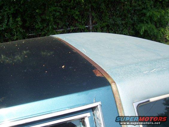 Close-up of a car's roofline showing a dark upper section and a lighter blue lower section with rust on the trim