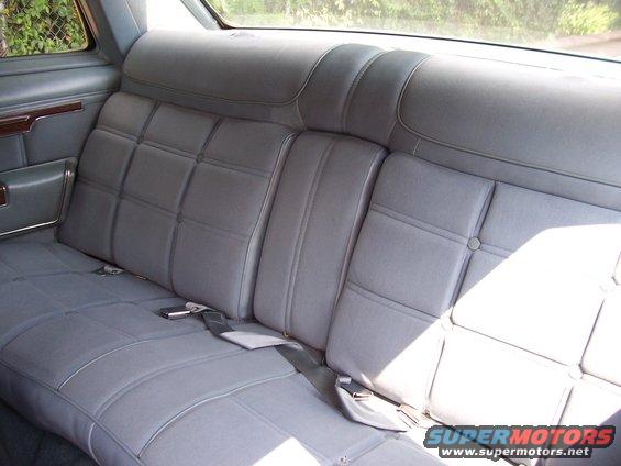 Gray vinyl rear bench seat with seatbelts in a car interior