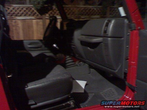 Interior of a red vehicle, showing the driver's side door, dashboard, and seat. The vehicle appears to be a Jeep Wrangler