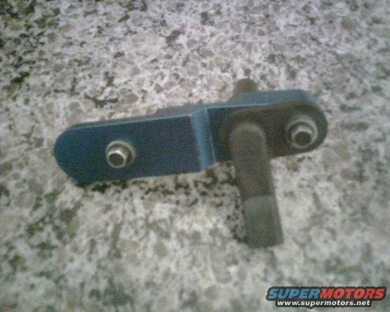 Blue metal automotive part with bolts and a rubber grommet on a speckled surface