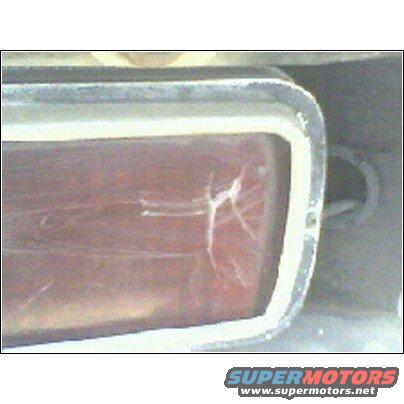 Cracked red tail light with chrome trim and a white gasket