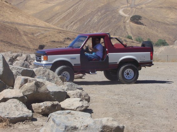 1991 Ford Bronco with doors removed, parked on dirt near rocks