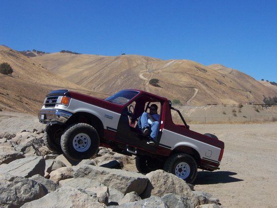 1991 Ford Bronco climbing over rocks with driver inside