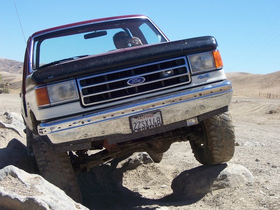 1991 Ford Bronco 4x4 off-roading over rocks, front 3/4 view