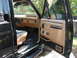 1987 Ford F-150 - The tan interior of a black pickup truck features a two-tone seat and a clean dashboard.