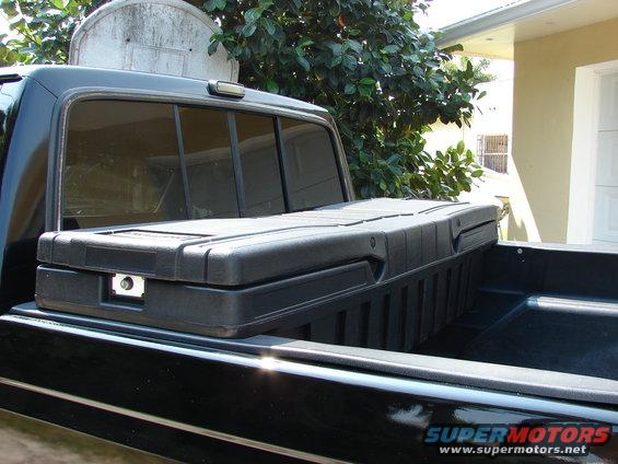 Black pickup truck bed with a black toolbox. Supermotors.net logo visible