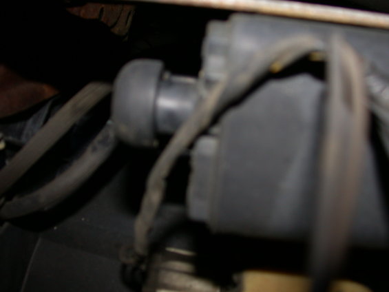 Close-up of a black vacuum hose connected to a gray plastic component