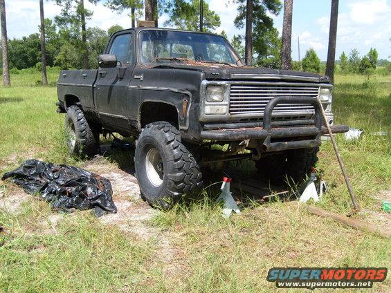 Black pickup truck with large tires and bull bar, lifted