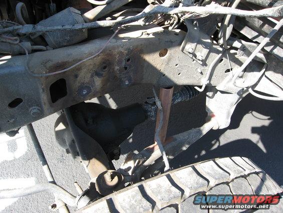 Rusty vehicle frame with visible suspension parts and tire tread