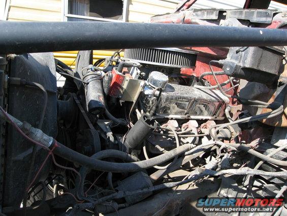 Engine bay with V8 engine, air filter, and radiator hoses. Red paint visible on engine block