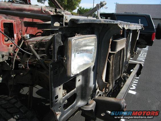 1986 Ford Bronco front end with engine exposed, disassembled. Another vehicle is parked behind
