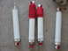 1986 Ford Bronco - A collection of four shock absorbers, two with red bellows, are displayed on a gray concrete surface.