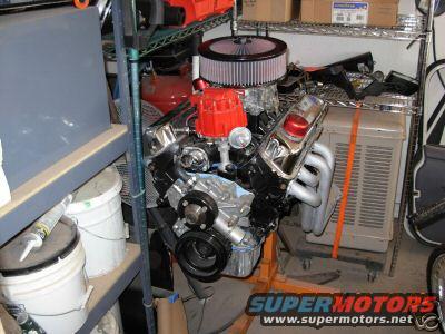 V8 engine with red distributor cap and chrome valve covers on an engine stand
