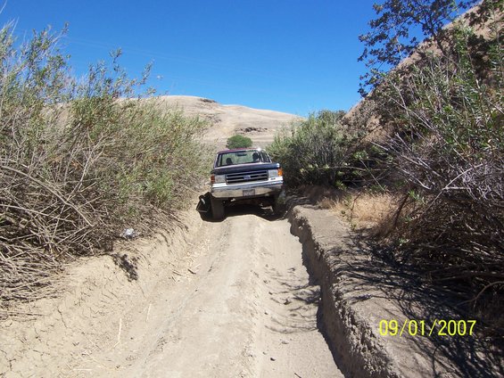 Ford F-Series truck driving on a dirt path with brush on either side. Date stamp reads 09/01/2007