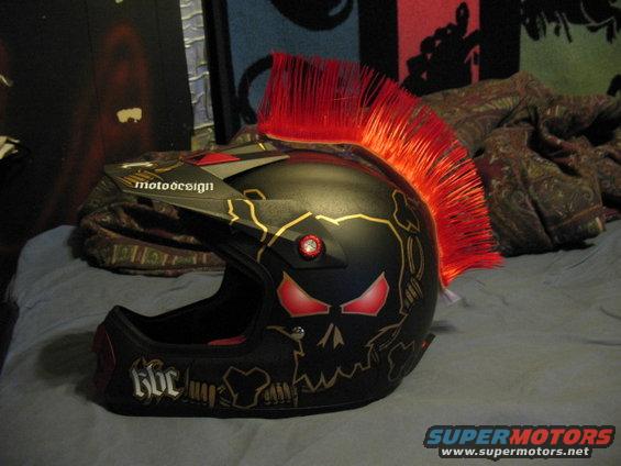 Black motorcycle helmet with red mohawk and skull graphics. Text reads 'motodesign' and 'Kbc'