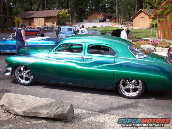 Green sedan with custom paint and chrome wheels parked outside