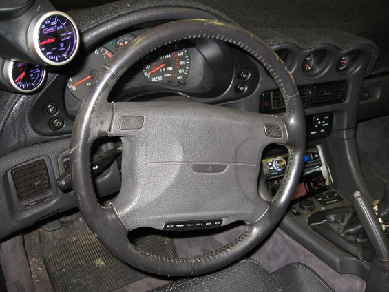 1991 Mitsubishi 3000GT interior with leather steering wheel, dashboard gauges, and aftermarket stereo