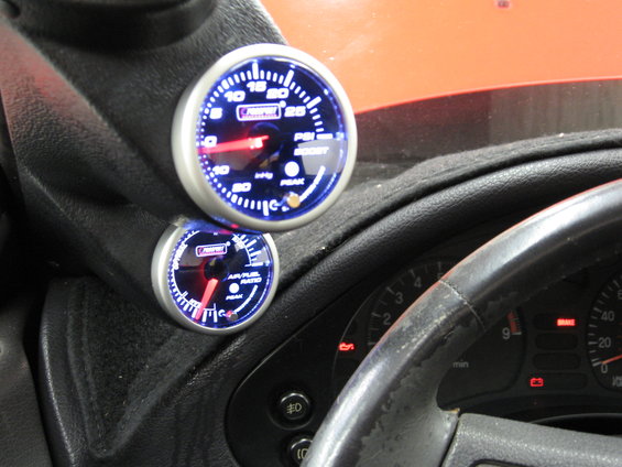 Car interior with boost and air/fuel ratio gauges mounted on the dash. Steering wheel and part of the dashboard are visible