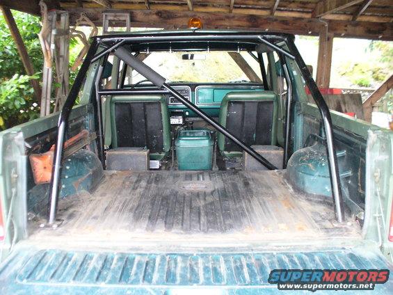 Green SUV interior and bed with roll cage, viewed from rear