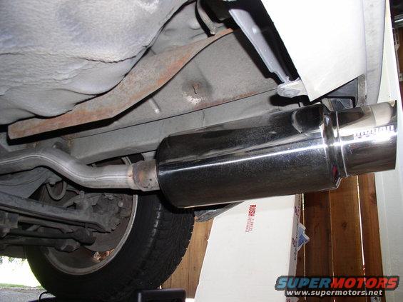 Close-up of a shiny aftermarket exhaust muffler and pipe under a vehicle