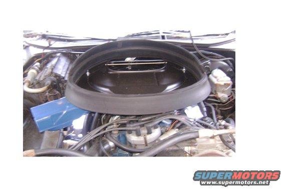 engine bay with large round black air cleaner housing over carburetor