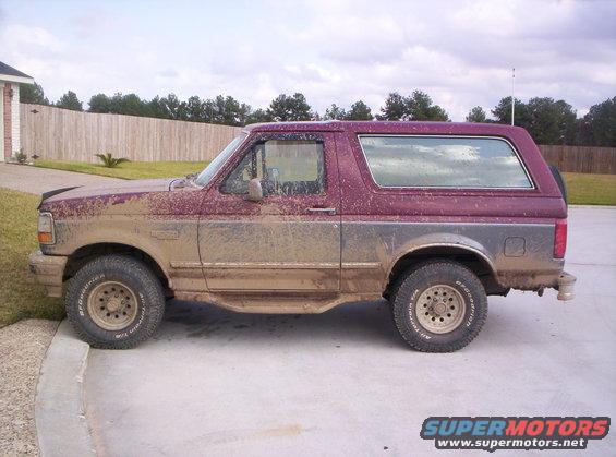 Maroon and grey 1993 Ford Bronco covered in mud, side view