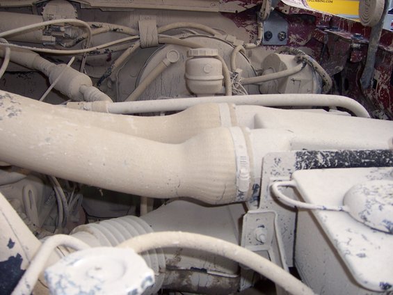 Dust-covered engine bay with hoses and brake fluid reservoir