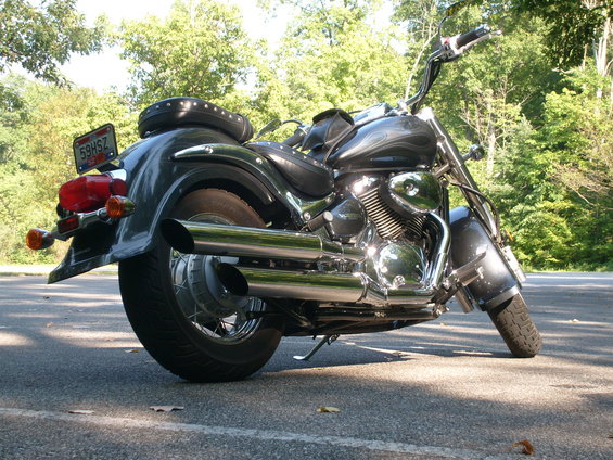 Motorcycle parked on asphalt with trees in background