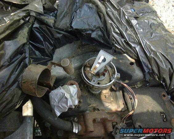 Engine block with distributor cap and rotor, some metal parts, and black plastic covering