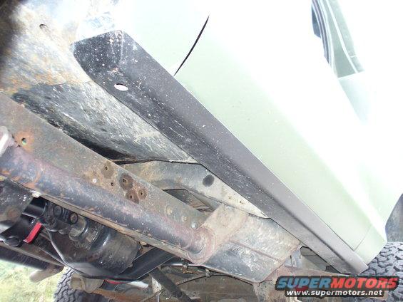 Undercarriage view showing rocker guard and frame components. Some rust is visible on the frame