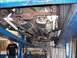 1978 Ford Mustang II - Car's undercarriage with dual exhaust system visible while on a lift at a repair shop.