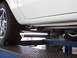 1978 Ford Mustang II - The underside of a white vehicle shows a shiny exhaust system and a tire on a car lift.