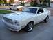 1978 Ford Mustang II - A white 1978 Ford Mustang II coupe is parked in a driveway, with a white pickup truck behind it.