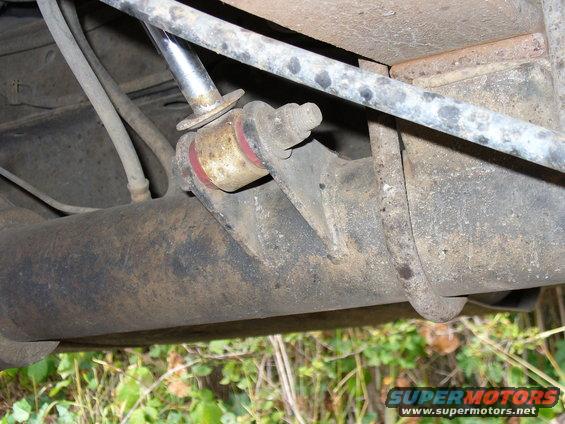Close-up of a rear axle shock mount with red bushings