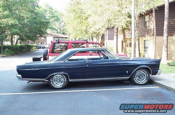 Dark blue 1965 Ford Galaxie coupe parked curbside, side view. Chrome trim, aftermarket wheels