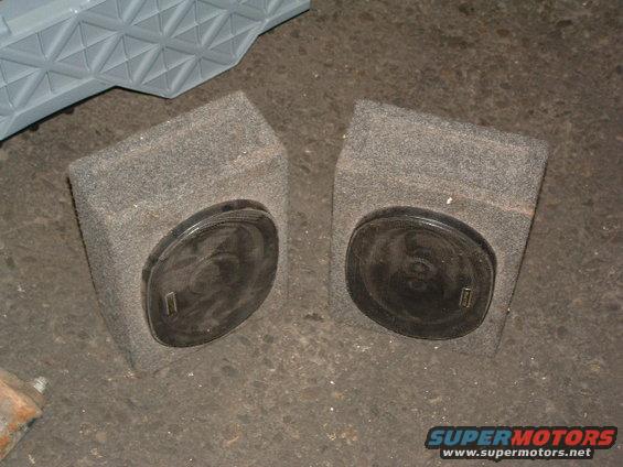 Two grey carpeted speaker boxes with black circular speakers, one on each