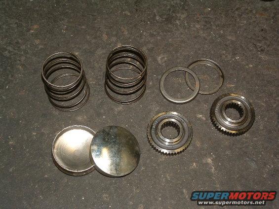 Transmission gears, springs, and caps on a dark surface
