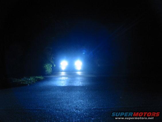 Car headlights illuminate a dark, wet road