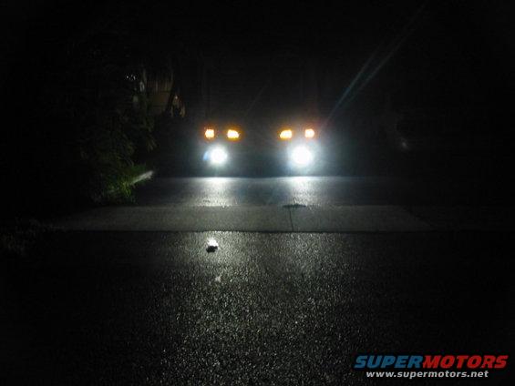 Vehicle front with bright headlights and amber turn signals at night