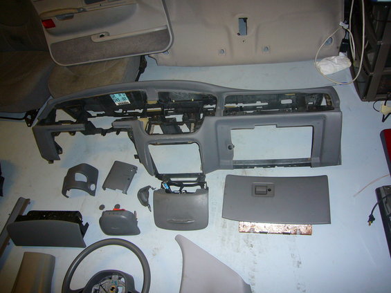 Disassembled dashboard and interior parts, including steering wheel and door panel