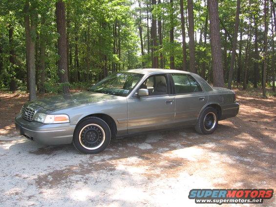 2000 Ford Crown Victoria parked on a dirt road in a wooded area