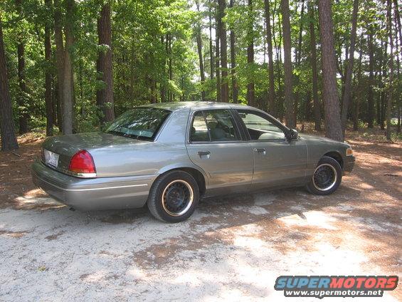 Gray 2000 Ford Crown Victoria parked on a dirt road in a wooded area